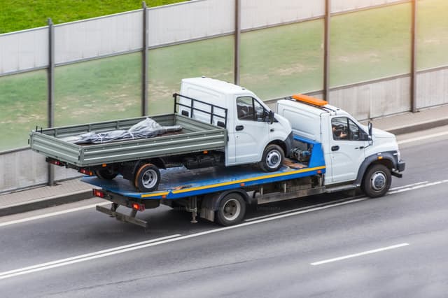Flatbed tow truck loading a car for recovery